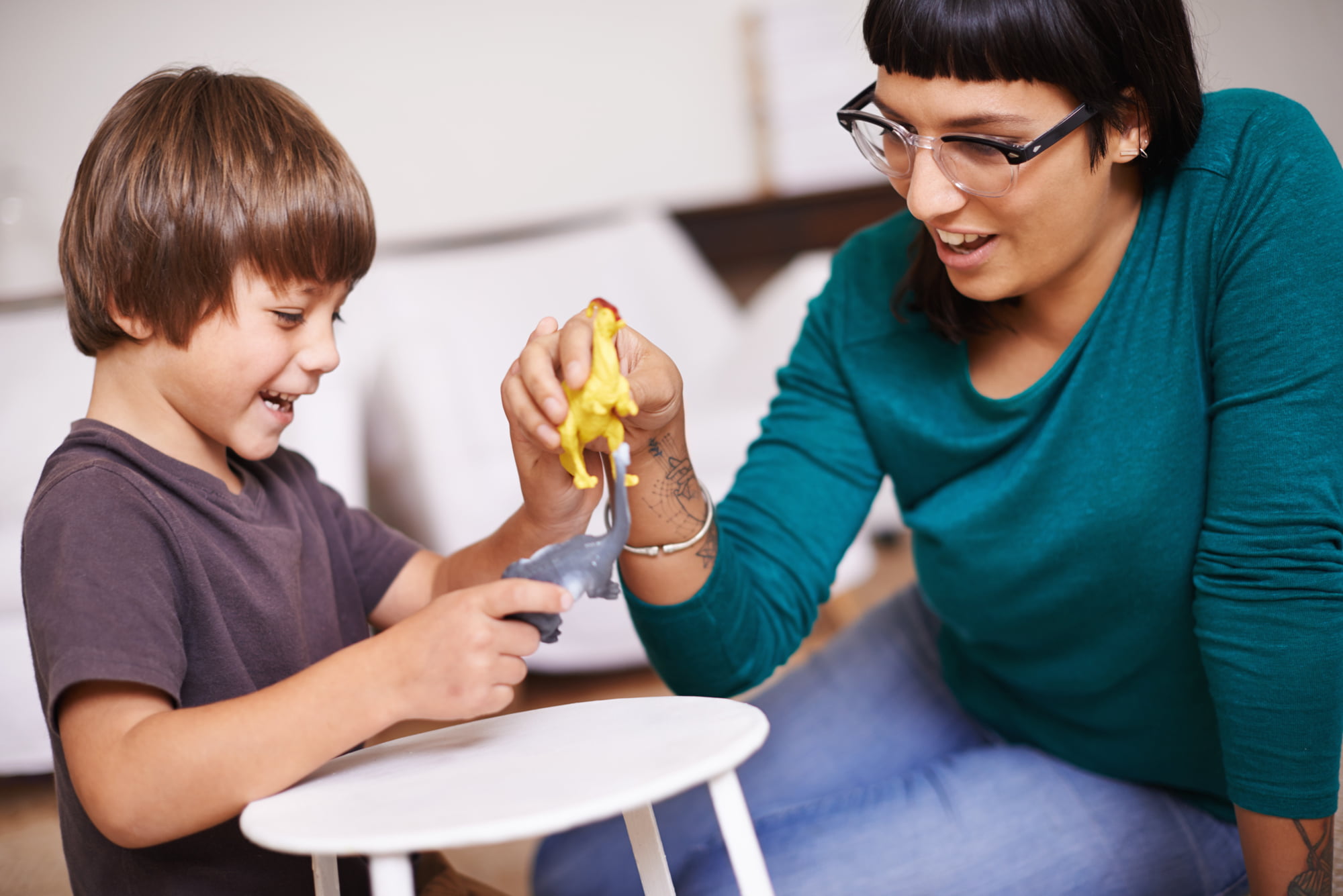 Adult and child communicating with each other using dinosaur toys